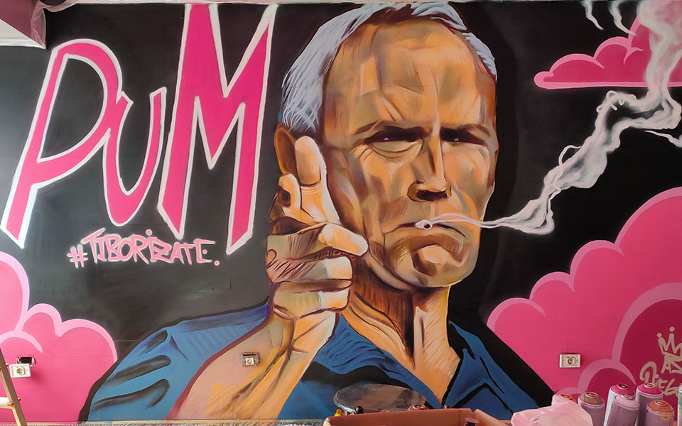 Graffiti de Clint Eastwood fumando y haciendo gesto con la mano de una pistola con la palabra PUM al lado