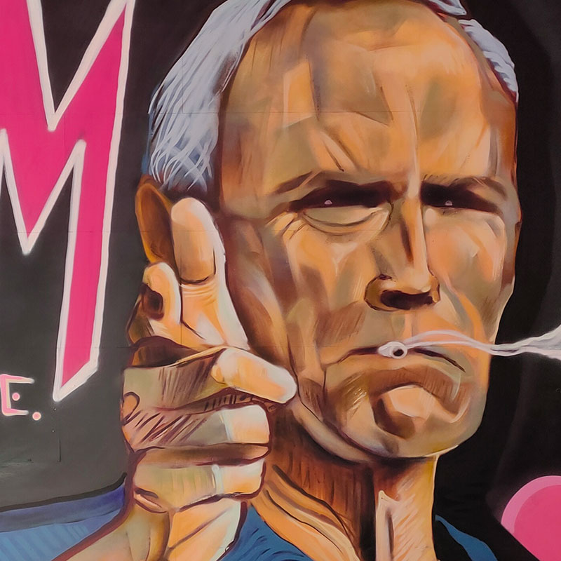 Graffiti de Clint Eastwood fumando y haciendo un gesto de disparar con la mano