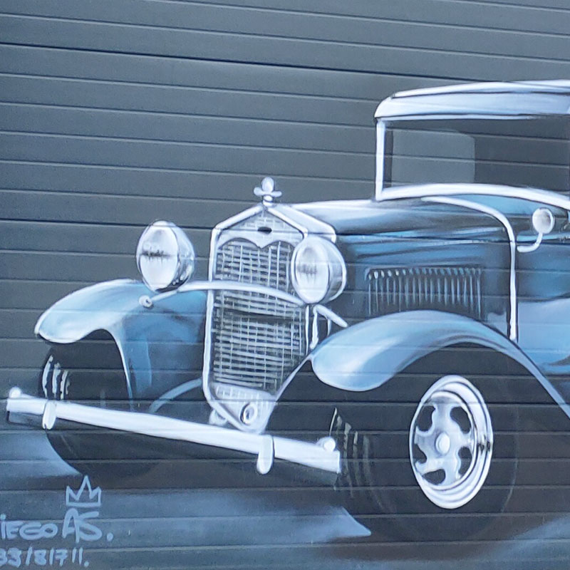 graffiti del morro de un coche antiguo en la verja de un garaje, plano detalle