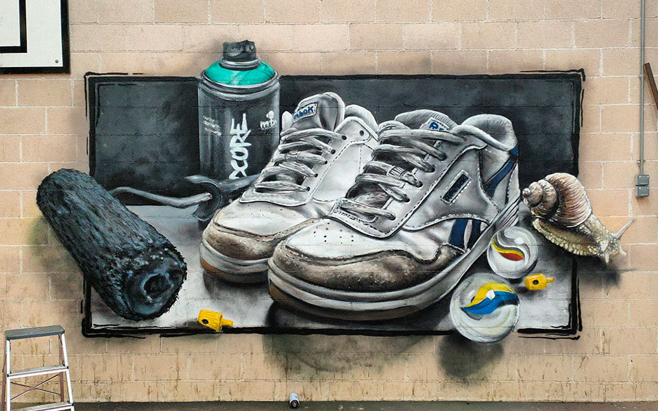 Graffiti de unas zapatillas con un bote de spray, un rodillo, canicas y un caracol