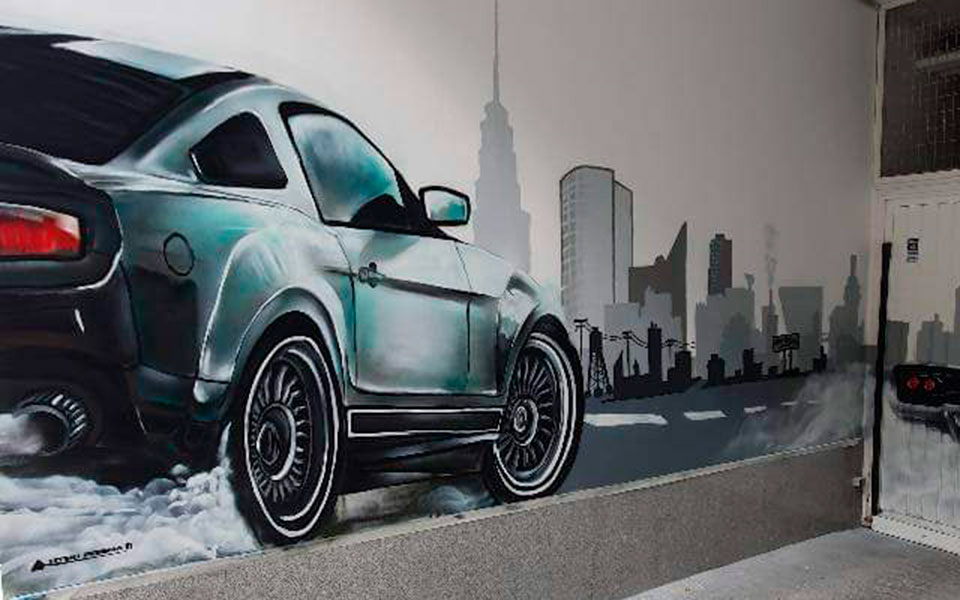 Graffiti en pared de garaje de un coche dirigiéndose a una ciudad